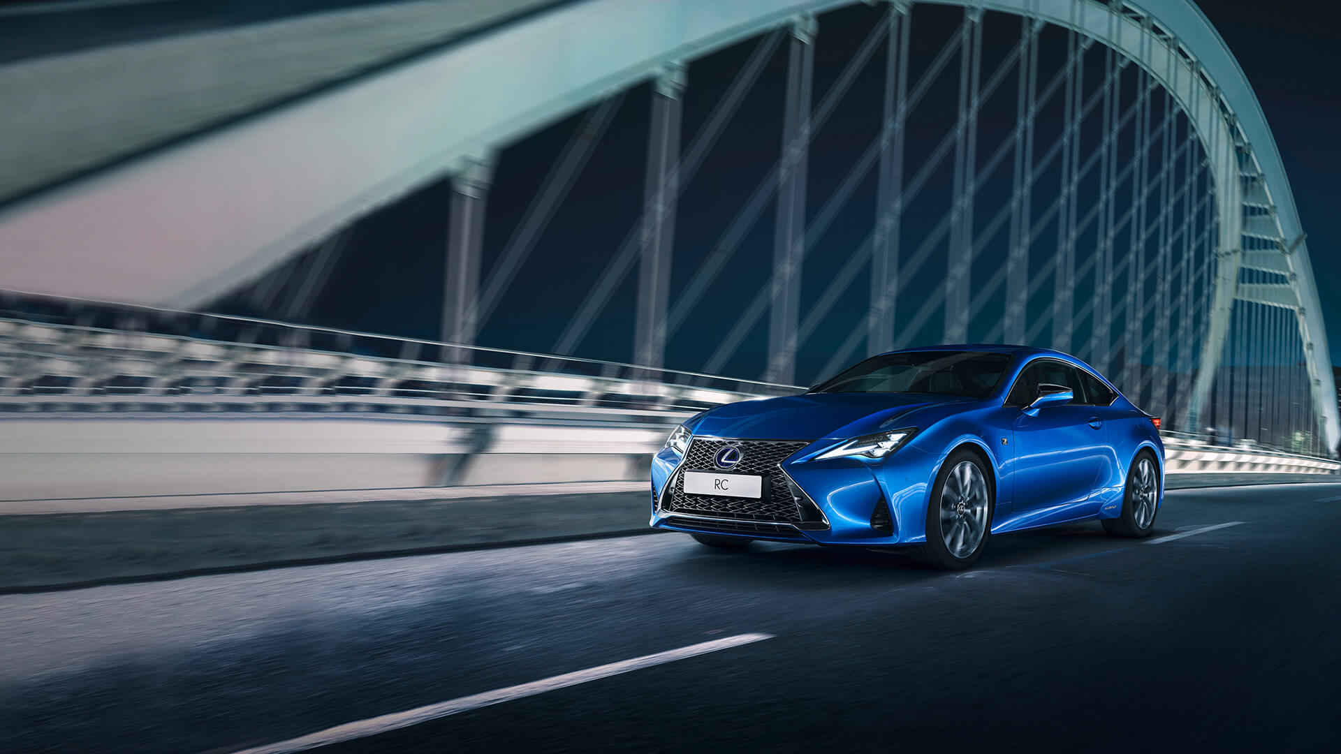 Blue Lexus RC being driven on a bridge at night.