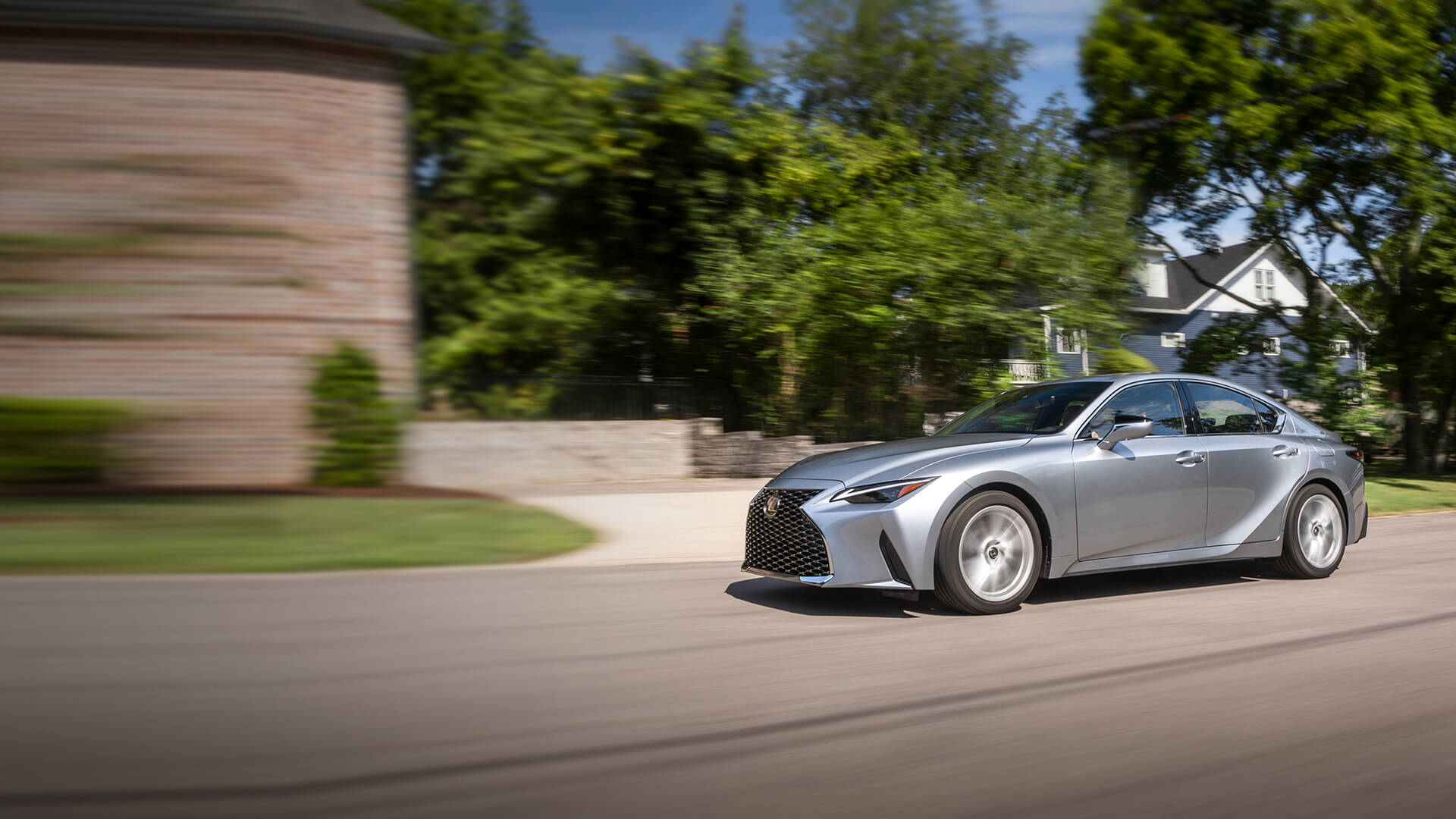Silver Lexus IS being driven in a neighbourhood.